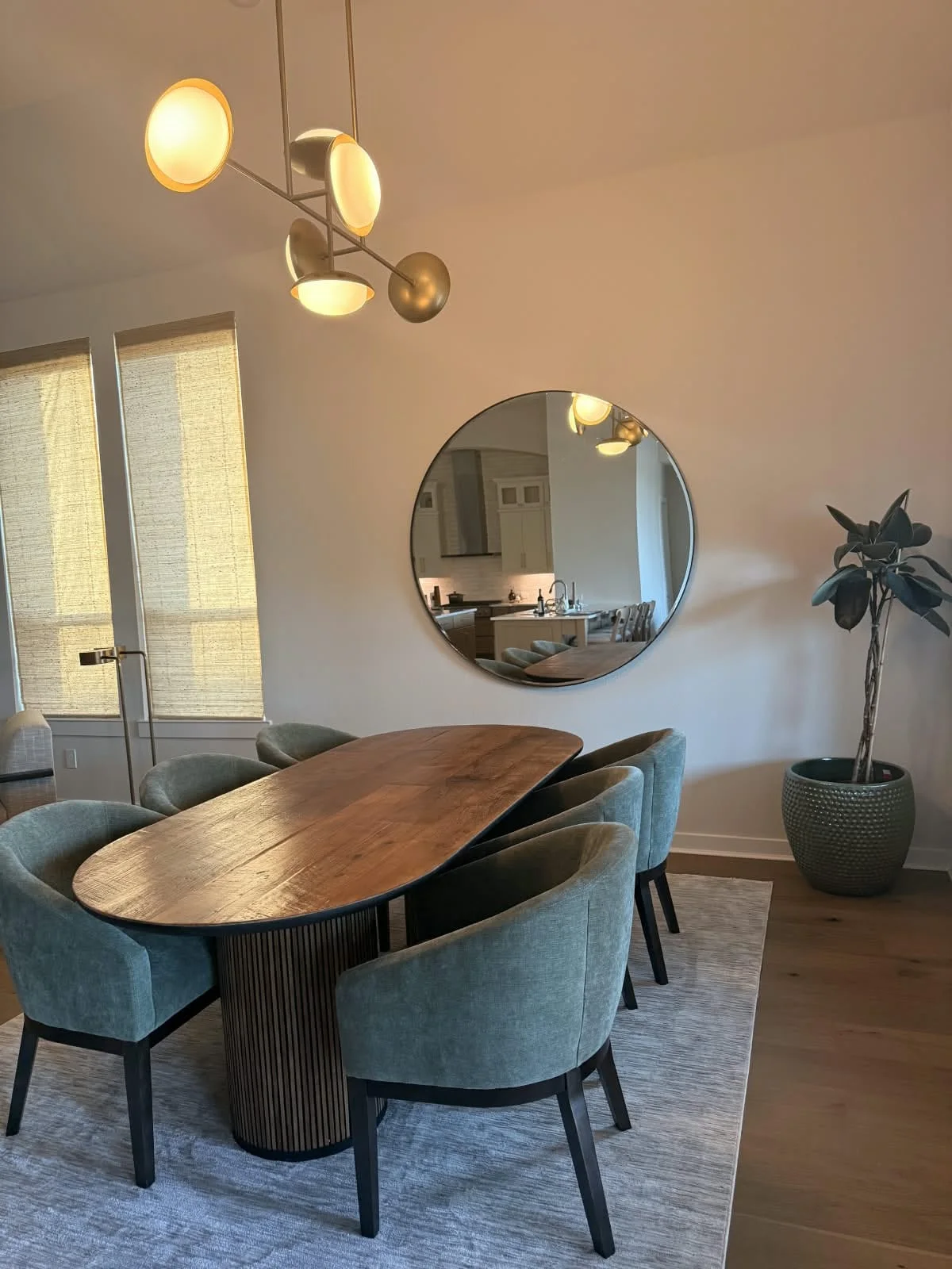 A restored and sealed oval wooden dining table surrounded by modern green chairs under a contemporary light fixture.