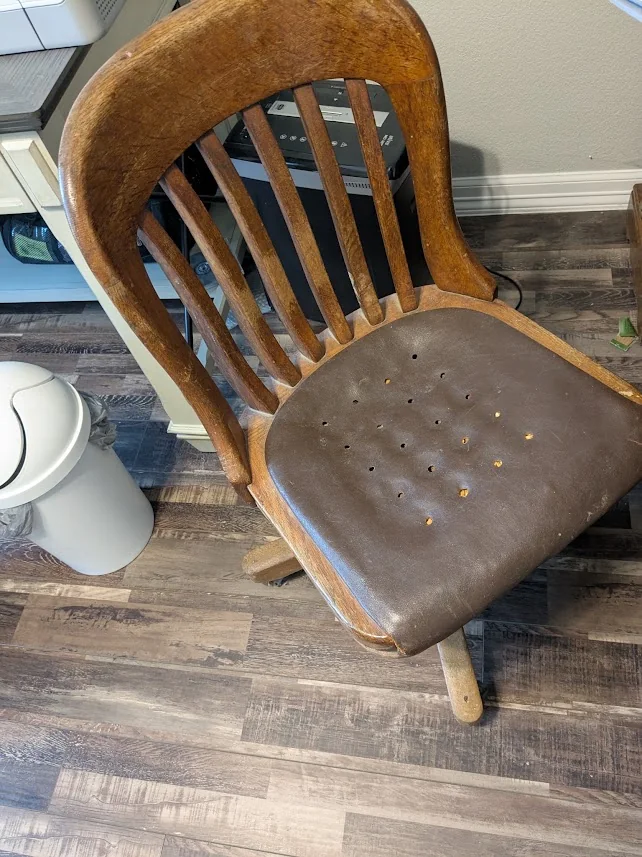 Worn vintage wooden swivel chair before mechanical repair, refinishing, and reupholstery.